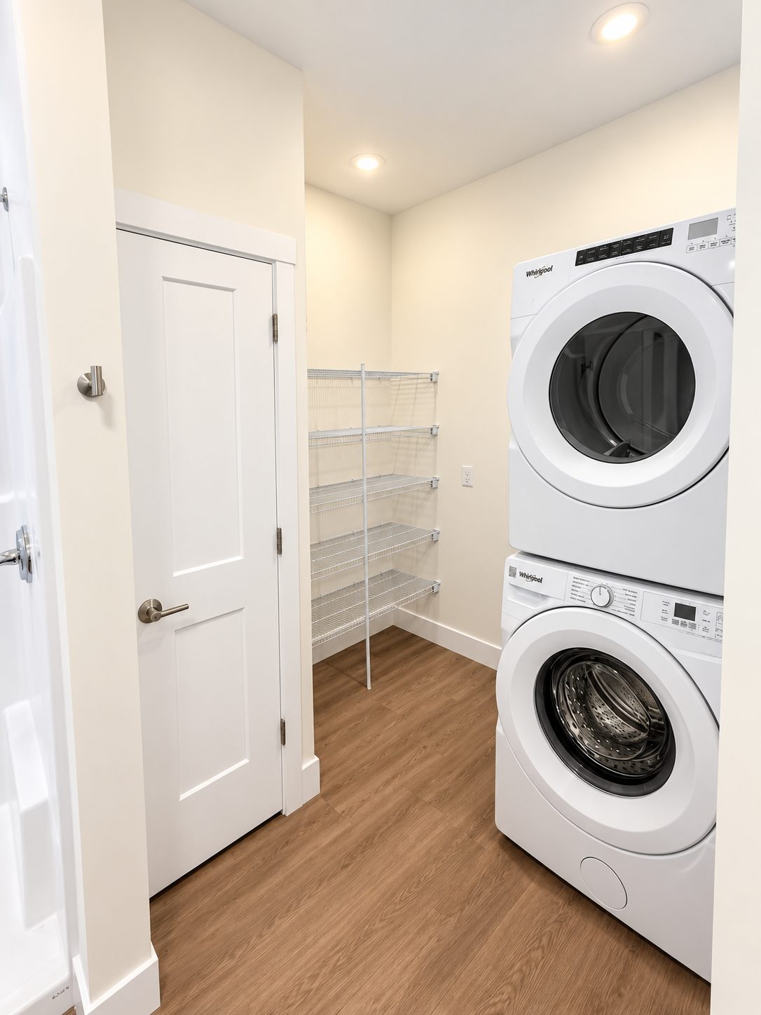 A laundry and storage closet in a GALE residence with a stacked Whirlpool washer and dryer and five tiers of wire shelving